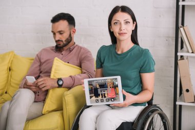 akıllı telefon kullanarak erkek arkadaşı yanında otururken online uygulama rezervasyon ile dijital tablet gösteren gülümseyen engelli kadın