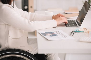 işyerinde otururken dizüstü bilgisayarda yazarak engelli iş kadını kırpılmış görünümü