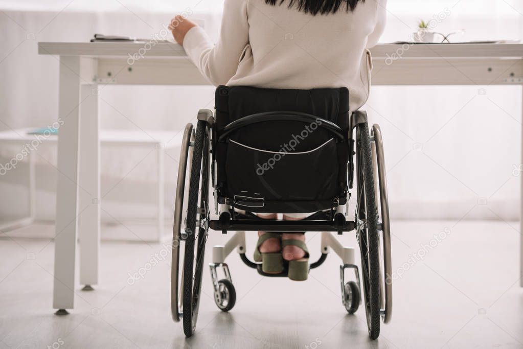 back view of disabled businesswoman sitting in wheelchair at workplace