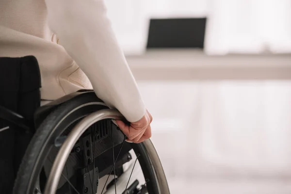 disabled businesswoman sitting in wheelchair near desk with laptop