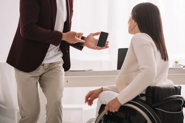 Engelli Kadını Boş Ekranlı Akıllı Telefon Gösteren Yöneticinin Kırpılmış Görünümü — Stok fotoğraf