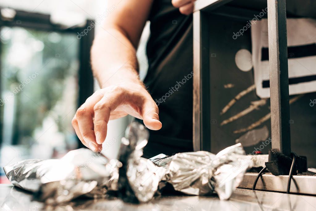 cropped view of man and doner kebabs in aluminium foil