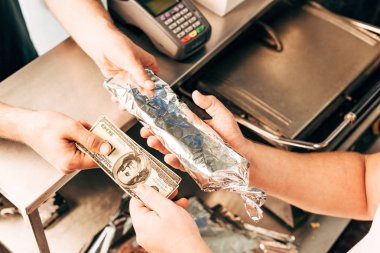 cropped view of man buying doner kebab in aluminium foil clipart