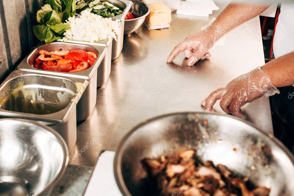 cropped view of cook in gloves at workplace with ingredients