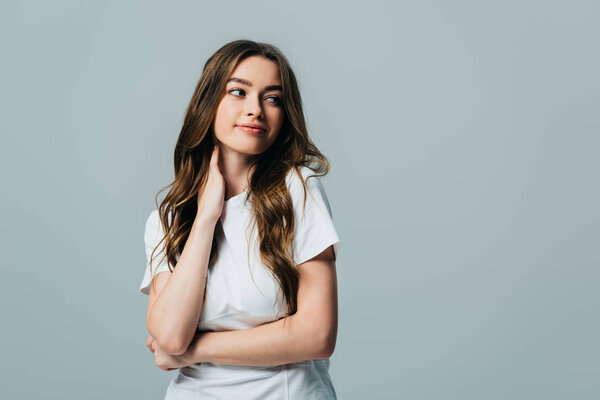 красивая улыбающаяся девушка в белой футболке, смотрящая вдаль на серую
