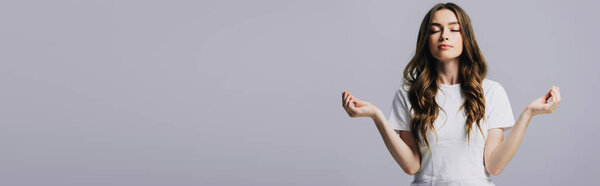 красивая девушка в белой футболке с закрытыми глазами медитирует изолированно на сером, панорамный снимок
