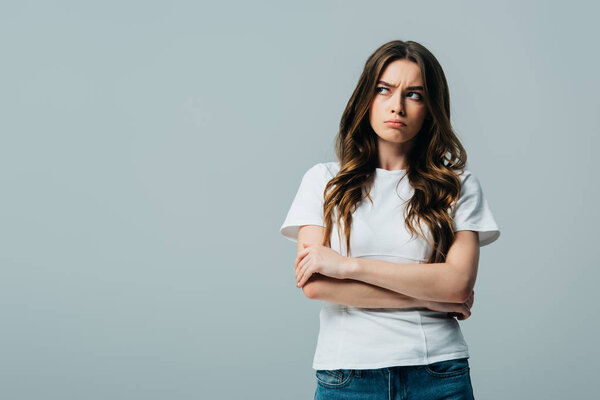 upset beautiful girl in white t-shirt with crossed arms looking away isolated on grey