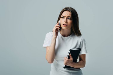 üzgün ve beyaz t-shirt güzel kız akıllı telefon konuşuyor ve gri izole dizüstü tutma