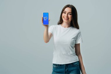 Kiev, Ukrayna - 6 Haziran 2019: gri üzerinde izole shazam uygulaması ile akıllı telefon gösteren beyaz t-shirt mutlu güzel kız