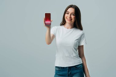 gri izole ticaret kursları uygulaması ile akıllı telefon gösteren beyaz t-shirt mutlu güzel kız