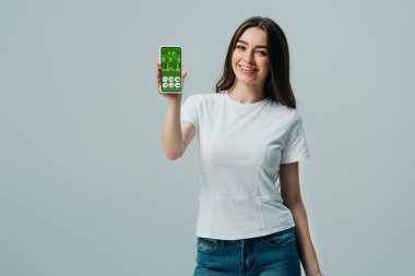 gri izole sağlık uygulaması ile akıllı telefon gösteren beyaz t-shirt mutlu güzel kız