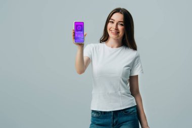 gri izole online alışveriş uygulaması ile akıllı telefon gösteren beyaz t-shirt mutlu güzel kız