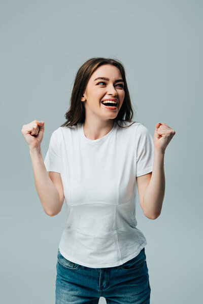 happy beautiful girl in white t-shirt showing yes gesture and looking away isolated on grey
