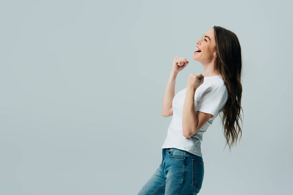 side view of happy beautiful girl in white t-shirt showing yes gesture isolated on grey