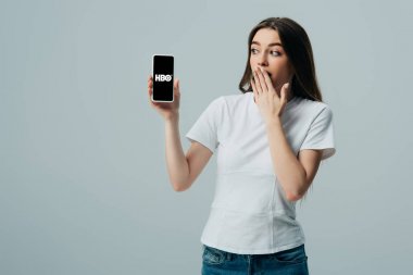 Kiev, Ukrayna - 6 Haziran 2019: gri izole Hbo uygulaması ile akıllı telefon gösteren beyaz t-shirt şok güzel kız