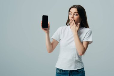 gri izole boş ekran ile akıllı telefon gösteren beyaz t-shirt şok güzel kız