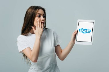 Kiev, Ukrayna - 6 Haziran 2019: gri izole skype uygulaması ile dijital tablet gösteren beyaz t-shirt şok güzel kız