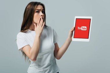 Kiev, Ukrayna - 6 Haziran 2019: gri izole youtube uygulaması ile dijital tablet gösteren beyaz t-shirt şok güzel kız