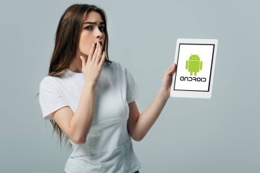 Kiev, Ukrayna - 6 Haziran 2019: gri izole android logosu ile dijital tablet gösteren beyaz t-shirt şok güzel kız