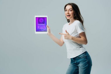gri izole online alışveriş uygulaması ile dijital tablet parmak ile işaret beyaz t-shirt gülümseyen güzel kız