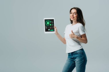 gri izole infografik uygulaması ile başparmak ve dijital tablet gösteren beyaz t-shirt gülümseyen güzel kız
