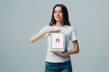 Kiev, Ukrayna - 6 Haziran 2019: Huawei gri izole ile dijital tablet gösteren beyaz t-shirt gülümseyen güzel kız