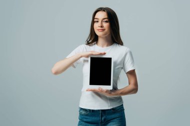 gri izole boş ekran ile dijital tablet gösteren beyaz t-shirt gülümseyen güzel kız