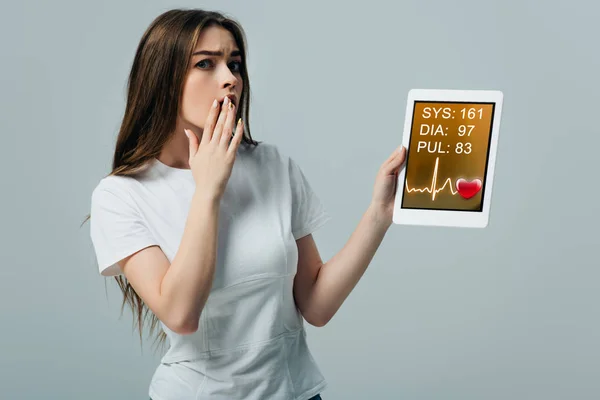 Šokovaná Dívka Bílém Tričku Zobrazující Digitální Tablet Kardiologickou Aplikací Izolovanou — Stock fotografie