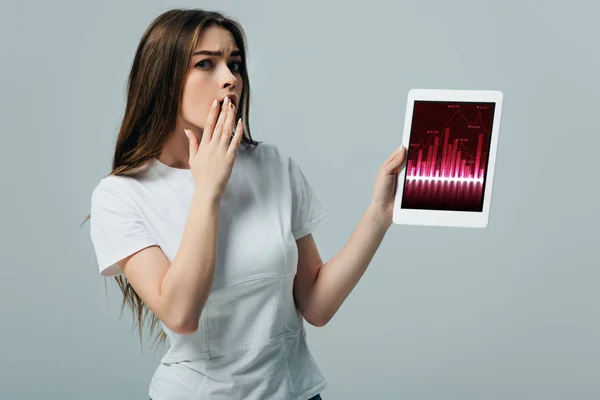 震惊美丽的女孩在白色T恤显示数字平板电脑与交易应用程序隔离在灰色 — 图库照片