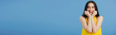 mavi, panoramik çekim izole bakarak yüzlerine yakın elleri ile sarı elbiseli mutlu güzel kız