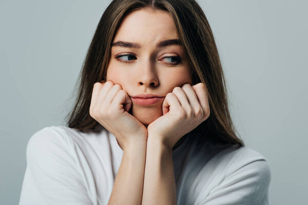 beautiful sad girl with hands near face looking away isolated on grey