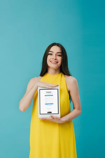 乌克兰 2019年6月6日 穿着黄色连衣裙的快乐美丽女孩展示数字平板电脑与Instagram应用程序隔离在绿松石 — 图库照片