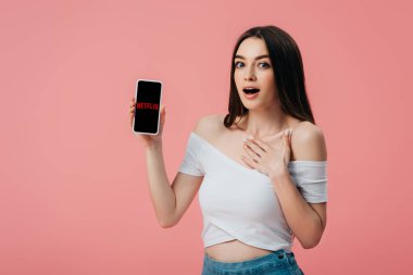 Kiev, Ukrayna - 6 Haziran 2019: Güzel şok kız pembe izole Netflix uygulaması ile akıllı telefon tutan