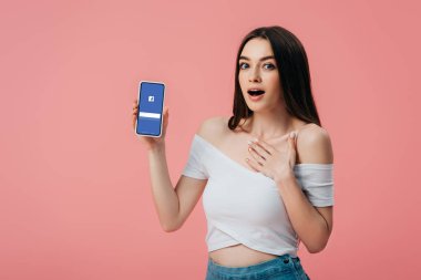 Kiev, Ukrayna - 6 Haziran 2019: pembe izole facebook uygulaması ile akıllı telefon tutan güzel şok kız