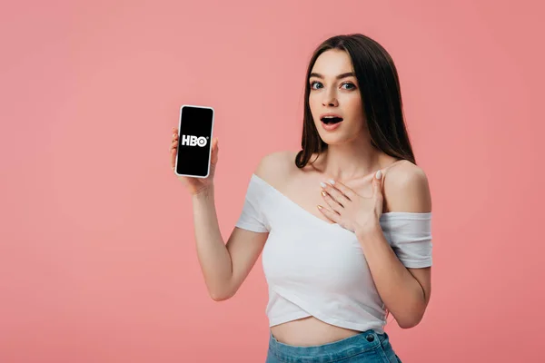 乌克兰 2019年6月6日 美丽的震惊的女孩拿着智能手机与Hbo应用程序隔离在粉红色 — 图库照片