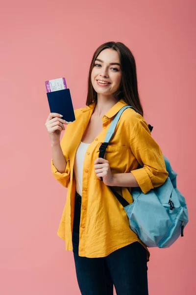 微笑的女孩与背包持有护照与机票隔离在粉红色 — 图库照片