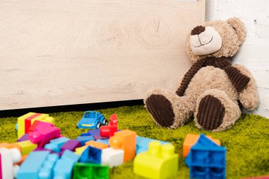 Peluş ayı ve yeşil halı üzerinde inşaat dağınık parçaları