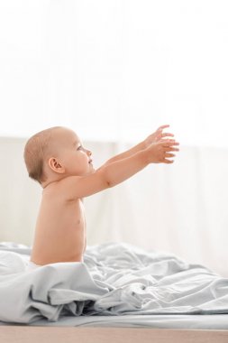 Bebek bezi gülümseyen ve ellerini kaldırarak sevimli küçük çocuğun Yan görünümü