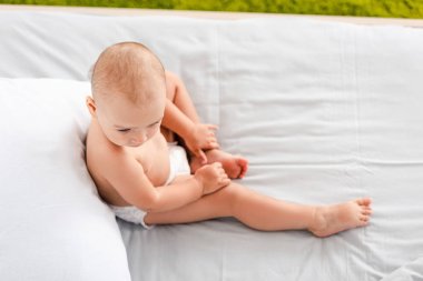 Yatakta oturan ve bacak dokunmadan bebek bezi güzel küçük bebek üst görünümü