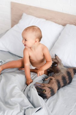 Sevimli küçük çocuk oturan ve oyuncak dinozor parmak ile işaret