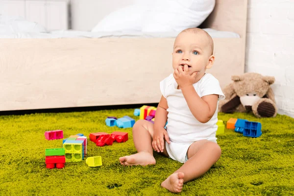 Симпатична Маленька Дитина Сидить Оточенні Іграшок Зеленій Підлозі — стокове фото