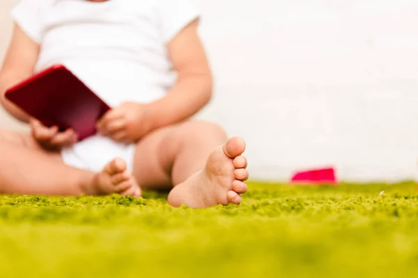 Partial View Little Barefoot Child Sitting Green Floor Holding Digital — Stock Photo, Image