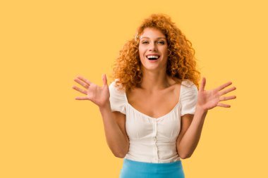 excited woman with red hair gesturing isolated on yellow clipart