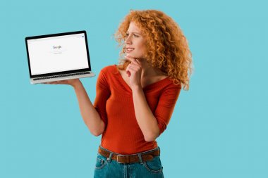 Kiev, Ukrayna - 16 Temmuz 2019: dalgın kızıl saçlı kadın google web sitesi ile dizüstü bilgisayar tutan, mavi izole 