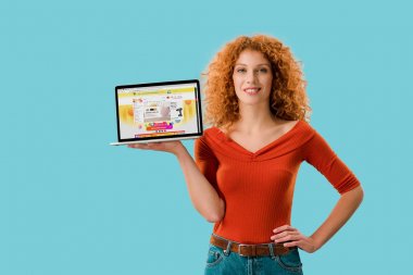 Kiev, Ukrayna - 16 Temmuz 2019: aliexpress web sitesi ile dizüstü bilgisayar tutan gülümseyen kızıl saçlı kadın, mavi izole 