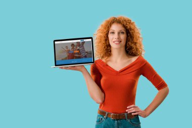 Kiev, Ukrayna - 16 Temmuz 2019: gülümseyen kızıl saçlı kadın couchsurfing web sitesi ile dizüstü bilgisayar tutan, mavi izole 