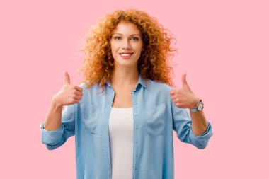 attractive redhead girl showing thumbs up isolated on pink clipart