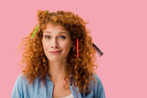 redhead student with pencils in hair isolated on pink