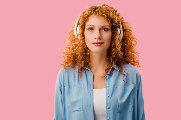 有吸引力的红发女人在耳机听音乐 隔离在粉红色 — 图库照片