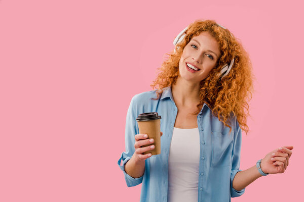 young redhead woman listening music in headphones, Isolated On pink